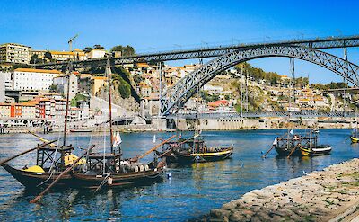 Boats rowing under a bridge, Porto, Portugal. Unsplash:Nick Karvounis