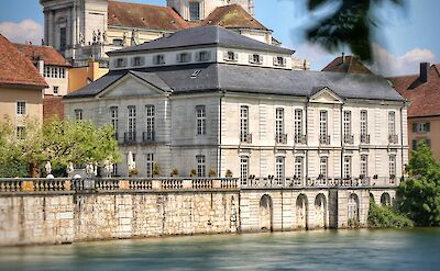 Historic stone building and St. Ursus Cathedral bordering the Aare River in Solothurn, Switzerland. Unsplash@Martin Zenker