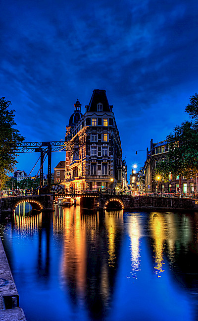 Amsterdam aglow in North Holland, the Netherlands. Photo via Flickr:Elyktra