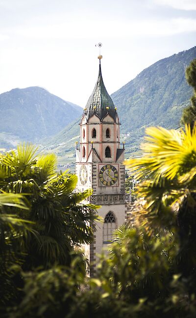 The ornate spire and clock tower of a church in Merano, Italy. Unsplash@Andreas Haslinger