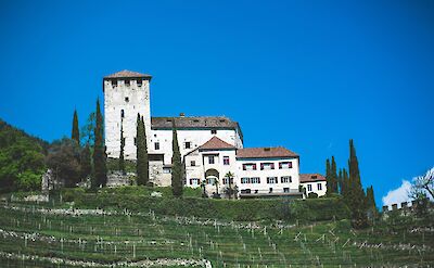 A stone castle and hillside vineyard near Lake Garda and the Adige River, Italy. Unsplash@Markus Spiske