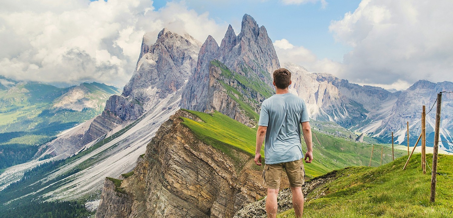 Man standing looking at mountain peaks. Unsplash@Joshua Earle