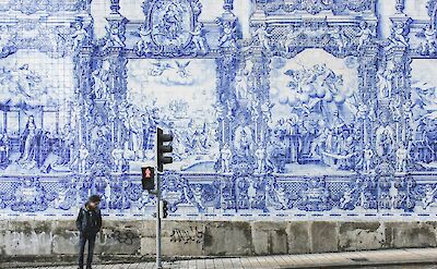 Man standing in front of a blue and white facade, Porto, Portugal. Unsplash:Dominik Kuhn