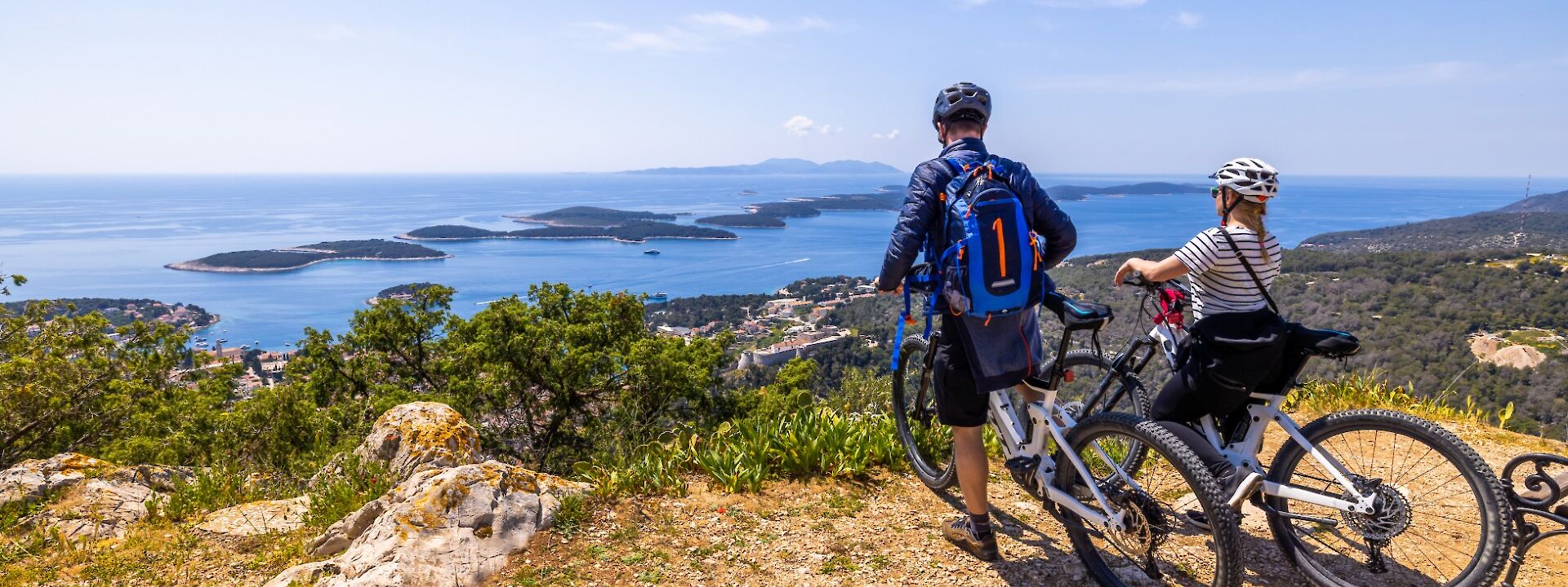 Two cyclists pause to admire coastal views on a bike tour. iStock@SimonSkafar
