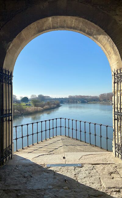 Admiring the river through an archway in Avignon, France bike tour. Unsplash@Elly Ch