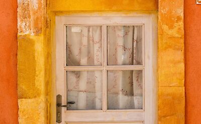 Door in a red archway in Roussillon, France bike tour. Unsplash@Henri Picot
