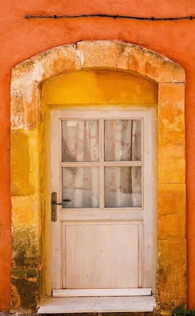 Door in a red archway in Roussillon, France bike tour. Unsplash@Henri Picot