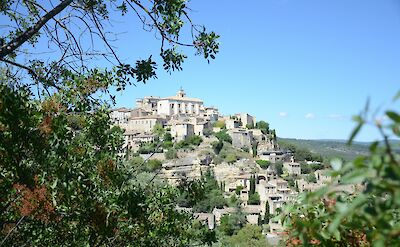 Gordes viewed through foliage, France bike tour. Unsplash@Andrea Konigsmann