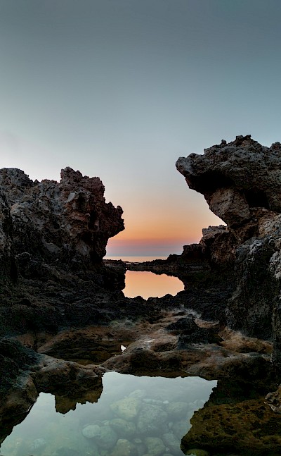 Sunset behind rocks in Milazzo, Italy. Unsplash@Giuseppe Famiani