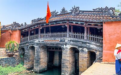 Woman standing next to the Japanese Bridge, Hoi An, Vietnam. Unsplash:Marina Lobato