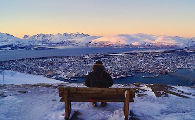 Person on a bench looking over Tromso, Norway. Unsplash: Daniel Volgel