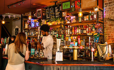 Bartender filling a glass of beer in Soho, London. CC: Eating Europe