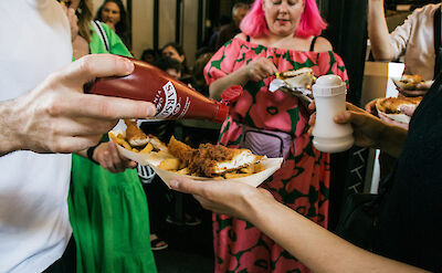 Seasoning a plate of fish and chips, London, England. CC: Eating Europe