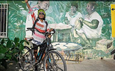 Posing with a bike next to a mural, Tulum, Mexico. CC:Mexico Kan Tours