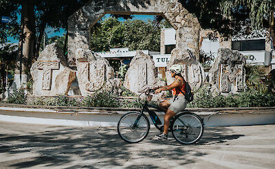 Riding next to a stone Tulum sign, Mexico. CC:Mexico Kan Tours