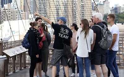 Tour guide pointing out the sights, Brooklyn Bridge, New York, USA. CC:Unlimited Biking