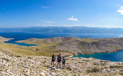 Hikers crossing high open terrain with Adriatic views. toST