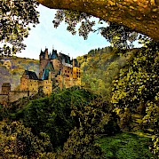 Rhine & Mosel By Bike & Boat - Eltz Castle seen through the trees, Treis-Karden, Germany. Unsplash@Peter Justinger