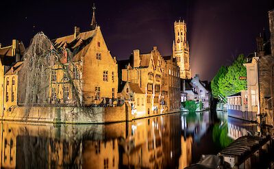 The illuminated Belfry rises behind centuries-old canal houses, Bruges. Pex@Nicolas Veithen