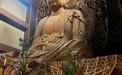 A wooden Buddha statue. Unsplash@Radim Jaksik
