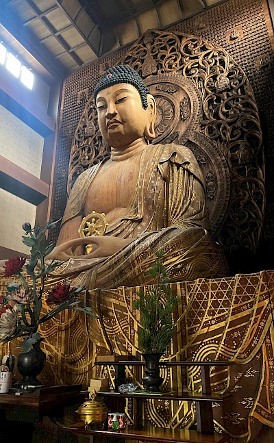 A wooden Buddha statue. Unsplash@Radim Jaksik