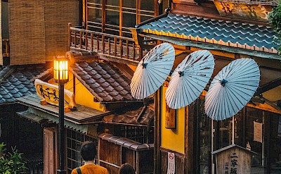 Traditional wooden buildings with paper lanterns and parasols. Unsplash@Romeo