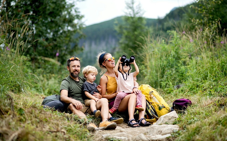 A child looking through binoculars on a family biking vacation. Unsplash@Getty Images