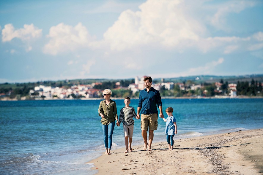 A family walking along a beach on a bike tour holiday. Unsplash@Getty Images