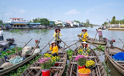 Women selling flowers from boats at a floating market. Pexels@QuandNguyenVinh