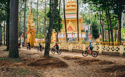 Riders pass a Khmer-style pagoda deep in the trees. toMBS