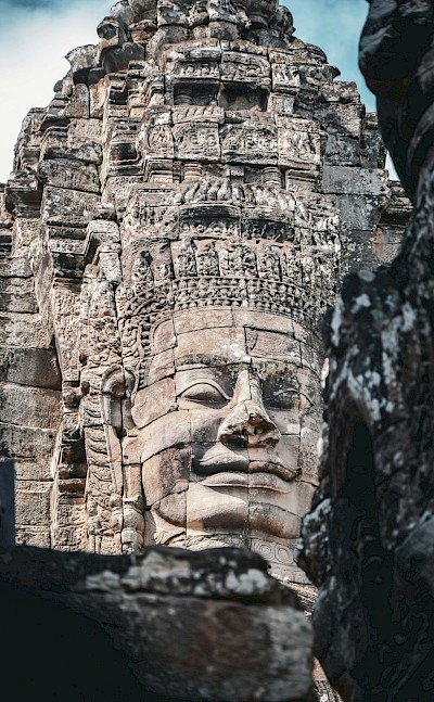 Large face on a temple at Angkor Wat, Cambodia bike tour. Unsplash@Sylwia Bartyzel