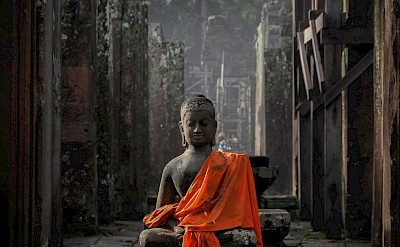 Statue in a robe at Angkor Wat, Cambodia bike tour. Unsplash@Vince GX