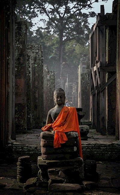 Statue in a robe at Angkor Wat, Cambodia bike tour. Unsplash@Vince GX