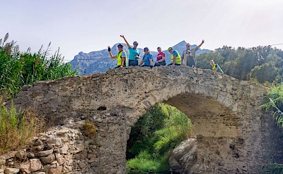 Cyclists celebrate at a historic stone bridge. toTN