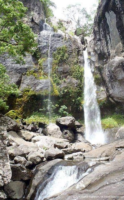 A hidden Fijian waterfall surrounded by mossy cliffs and rainforest. to-FIT