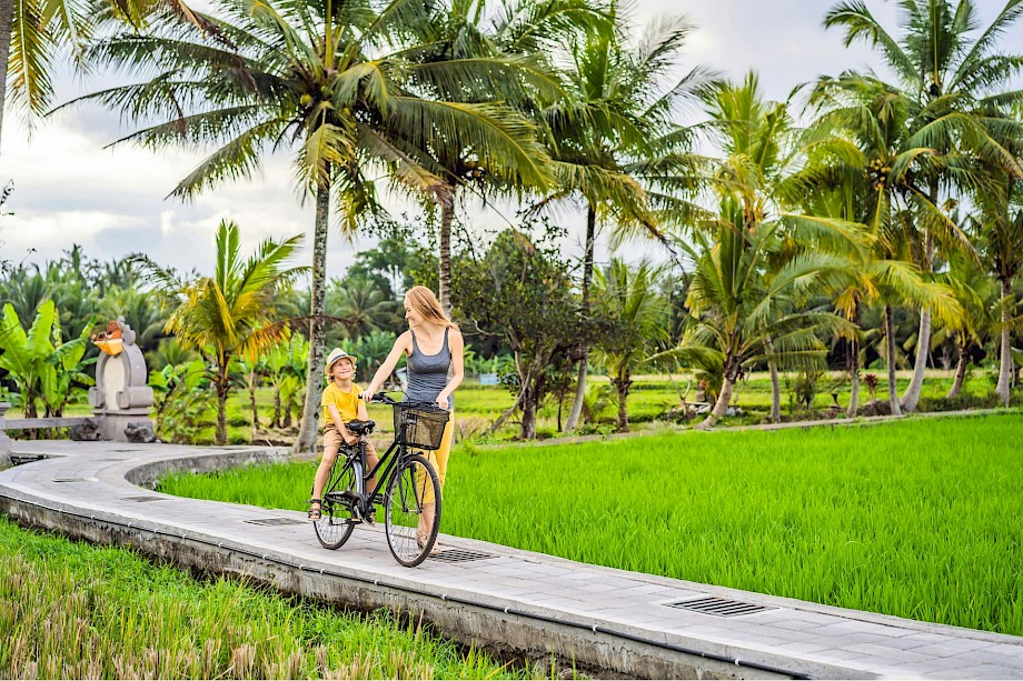 Woman pushing her son on a bicycle in Asia. Unsplash@Getty Images