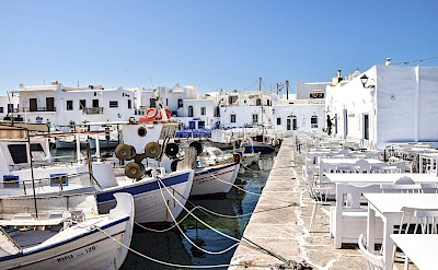 Naoussa harbor in Paros, featuring fishing boats, Cycladic architecture, and waterfront cafés. pexels@AXPPhotography