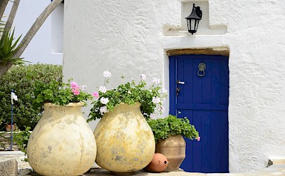 Traditional Cycladic doorway with whitewashed walls and pottery accents. toIH