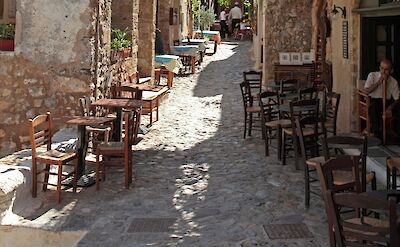 Quiet cobblestone street lined with caf&eacute;s in Monemvasia old town. unsplash@VasilisCaravitis
