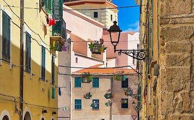 Historic street in Alghero's old town with views of the Cathedral of Santa Maria. pexels@DomenicoAdornato