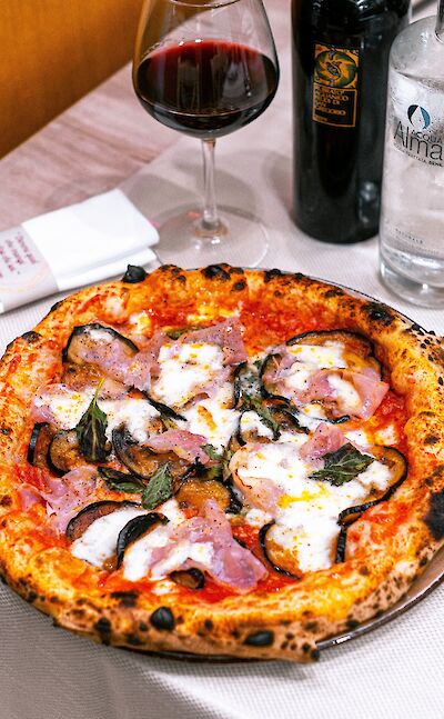 Wood-fired pizza and a glass of wine. Pexels@Emilianovittoriosi