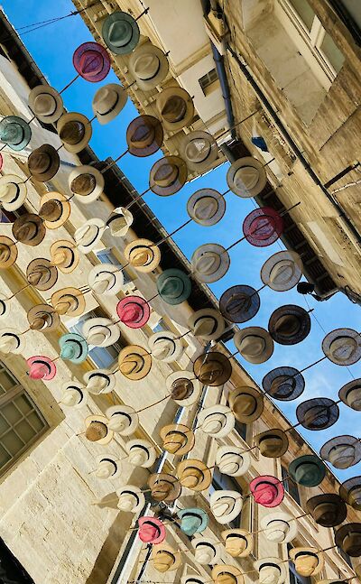 Colorful hats decorating a street in Avignon. unsplash:Studimajo