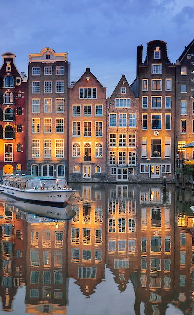 Historic canal houses glow at dusk in Amsterdam. Pixabay:Lubovlisitsa