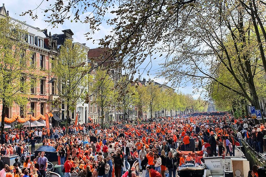 King's Day crowds lining the canals of Amsterdam, Netherlands. Unsplash@Abhay Rautela