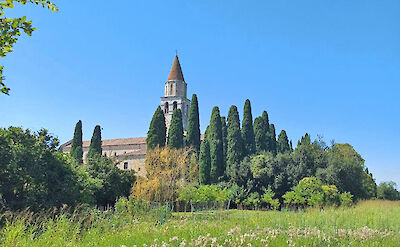The historic Basilica of Aquileia, a UNESCO World Heritage Site, surrounded by cypress trees. cc:to