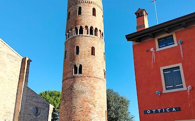 Historic bell tower and colorful buildings in Caorle, Italy. cc:to