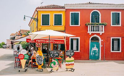 Colorful buildings and outdoor caf&eacute;s on the island of Burano, Venice. pexels:Helen1