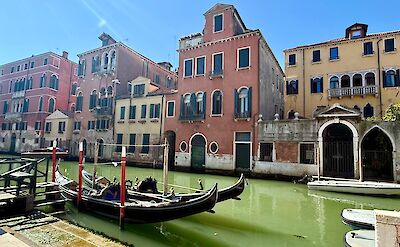 Colorful Venetian buildings and gondolas along a quiet canal. cc:Tripsite