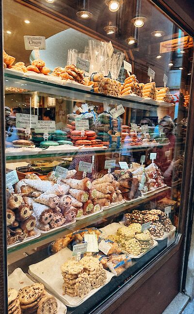 Traditional Italian pastries and sweets displayed in a bakery window. pexels:AlinaKomarevska