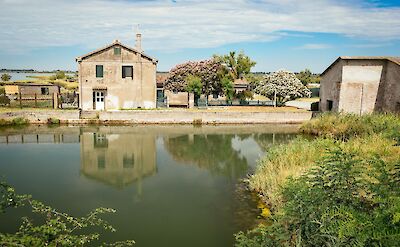 Traditional farmhouse beside a quiet waterway in northeastern Italy. cc:to